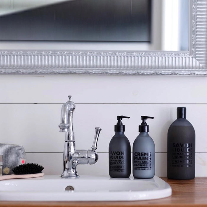 A frosted grey pump bottle of COMPAGNIE DE PROVENCE's Savon Liquide De Marseille Cashmere Soap by CIE LUXE BRANDS features a black dispenser and contains 300 ml (10 fl. oz.) of soap infused with luxurious botanical oils.