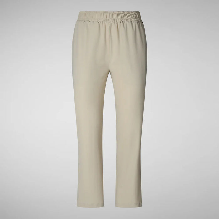 A person with shoulder-length hair and a neutral expression wears a white long-sleeve shirt, SAVE THE DUCK MILAN PULL ON PANT in black wrinkle-free fabric, and black slip-on shoes. Their hands rest at their sides against a plain background.
