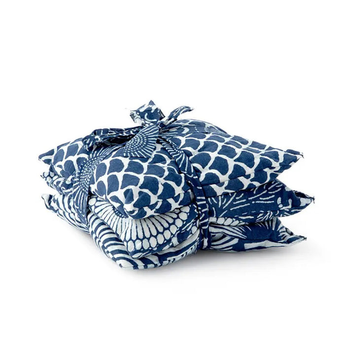 Three square pillows in blue and white patterns—a geometric wave, a radial fan motif, and circular flower-like shapes adorned with leafy details—ideally complement the use of BAUDELAIRE's Chamomile Sleep Sachets by infusing relaxation into your sleep sanctuary.