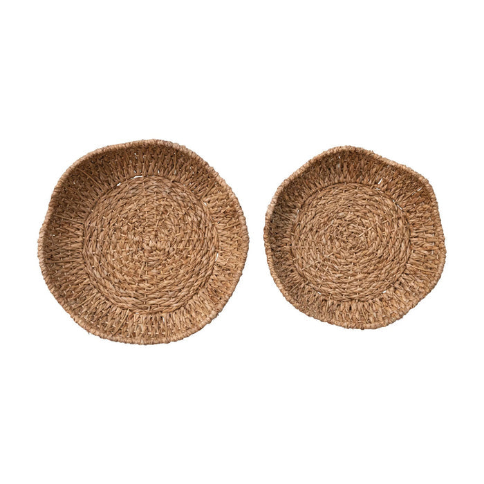 Two round, natural brown BRAIDED BANKUAN BOWLS WITH SCALLOPED EDGE by CREATIVE COOP are displayed side by side on a white background, with the large basket slightly bigger than the other.