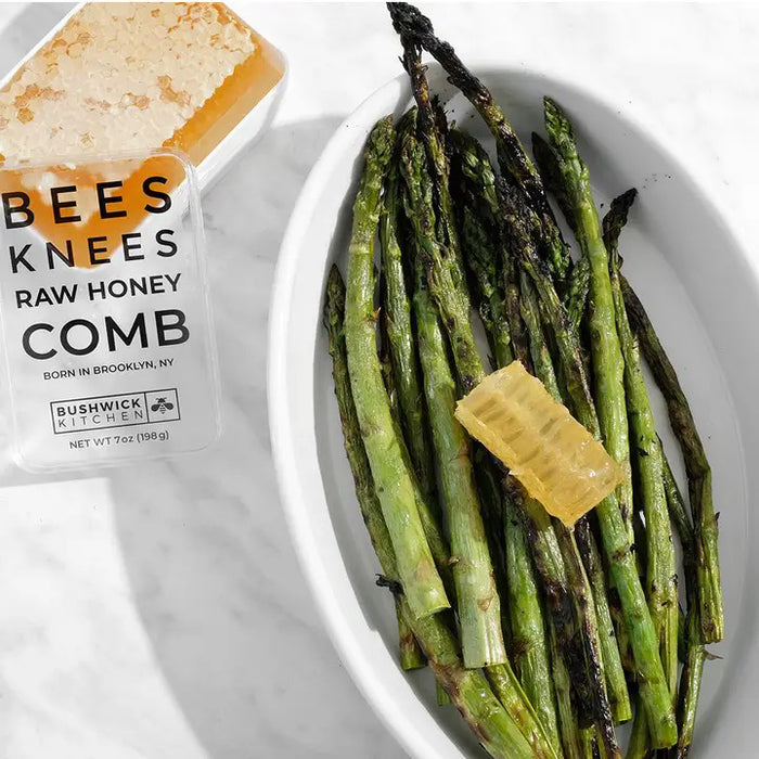 A rectangular container of BUSHWICK KITCHEN - 'BEES KNEES' RAW HONEYCOMB stands upright on a white background, featuring 100% raw honeycomb inspired by acacia honey and crafted in Brooklyn, NY.