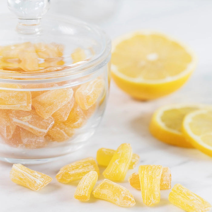 A 2.5oz (60g) bag of BUTTERFIELDS - LEMON BUDS hard candy by BUTTERFIELDS, featuring a large lemon with a green leaf on the front. The gluten-free packaging highlights a hand-squeezed lemonade flavor.