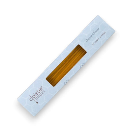 A white, rectangular box containing Cloister Honey - Orange Blossom Honey Straws. The box features a subtle honeycomb pattern and a transparent window showcasing the healthily snackable honey straws inside. Text on the box reads "Cloister Honey" and "12 Honey Straws," highlighting 100% pure, raw natural honey.