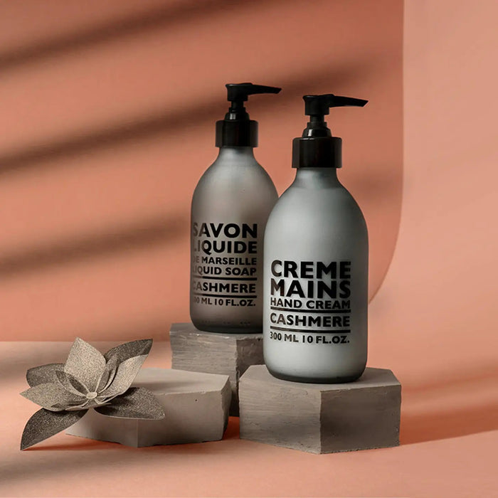 A grey bottle with a black pump, labeled "CIE LUXE BRANDS COMPAGNIE DE PROVENCE CASHMERE HAND CREAM," contains shea butter and woody, spicy notes; it holds 300 ml (10 fl oz).