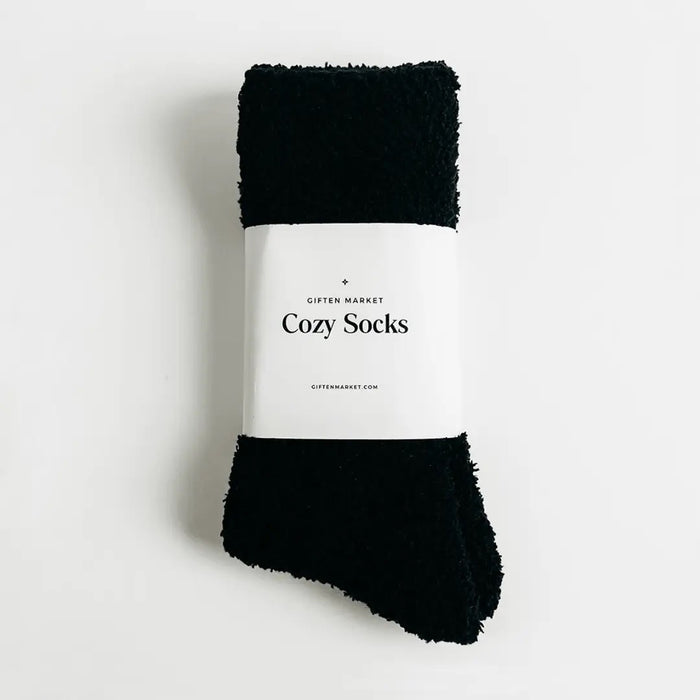 Beige fuzzy socks made from soft plush material are wrapped in a white "Cozy Cloud Socks" label displaying "Giften Market" and "GIFTENMARKET.COM." These women's socks are neatly folded and viewed from above on a plain background.