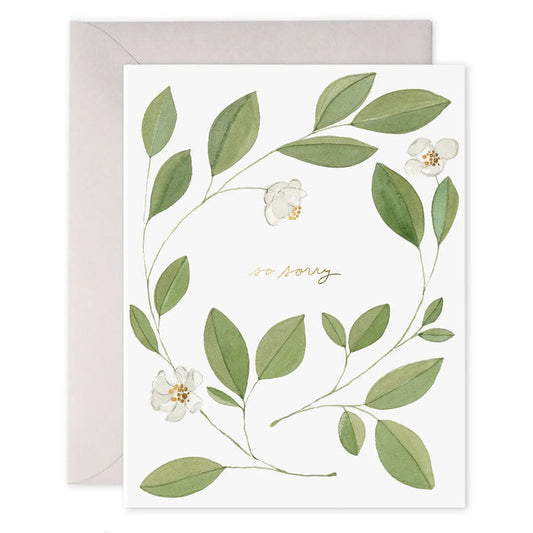 The E. FRANCES PAPER Magnolia Condolence Card features "so sorry" in elegant gold cursive, framed by a wreath of green magnolia leaves and white flowers, and includes a beige envelope.