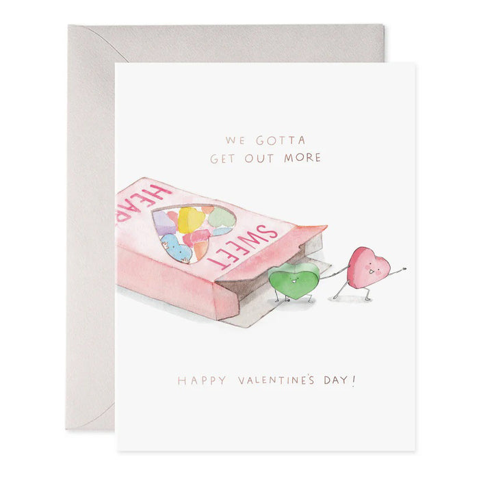 The "We Gotta Get Out More" greeting card by E. Frances Paper showcases a pink "SWEET HEARTS" candy box with two heart-shaped candies stepping out. Crafted on luxe heavyweight paper, it features the playful text above and gold foil elegance beneath with "HAPPY VALENTINE'S DAY.