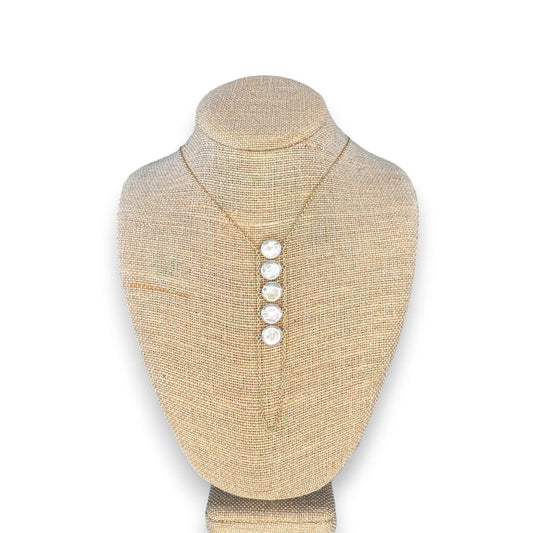 A woman in a beige top wears the GOLDISH - LADDERS TO BLISS PEARL NECKLACE, featuring round white stones, as she poses with crossed arms and a turned head, embodying balance and harmony.