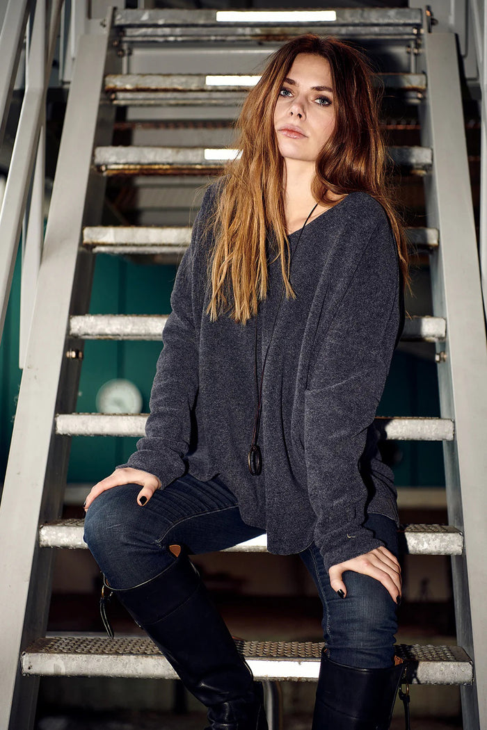 The HENRIETTE STEFFENSEN FLEECE V NECK SWEATER by HENRIETTE STEFFENSED is a loose-fitting, long-sleeve black sweater with a cozy V-neck, shown on a hanger and styled with a circular pendant necklace.