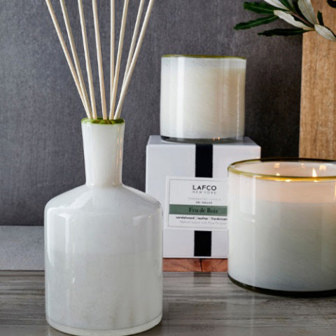 The LAFCO Ski House Feu de Bois Diffuser features a cream bottle, black ribboned box, and reeds to diffuse a sophisticated smoky leather scent.