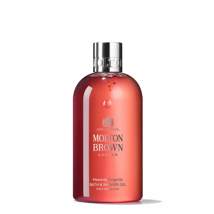 A transparent red bottle of Molton Brown's Heavenly Gingerlily Bath and Shower Gel, adorned with a silver cap and white text, beautifully captures exotic wanderlust.