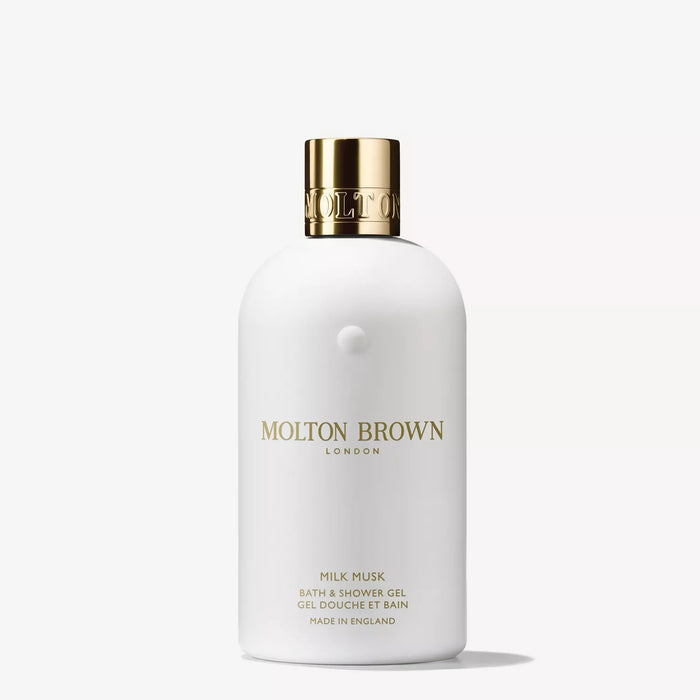 A white bottle of MOLTON BROWN - MILK MUSK BATH & SHOWER GEL with a gold cap and minimalist gold text, highlighted against a plain white background, offers a luxurious blend of tonka bean and white musk. Brand: MOLTON BROWN.