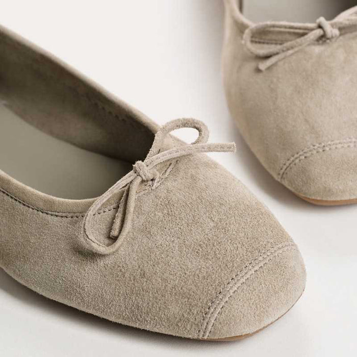The REQINS - HARMONY BALLERINA FLATS by REQINS are shown in taupe suede with a small front bow and low heel, displayed in side profile against a plain light background.