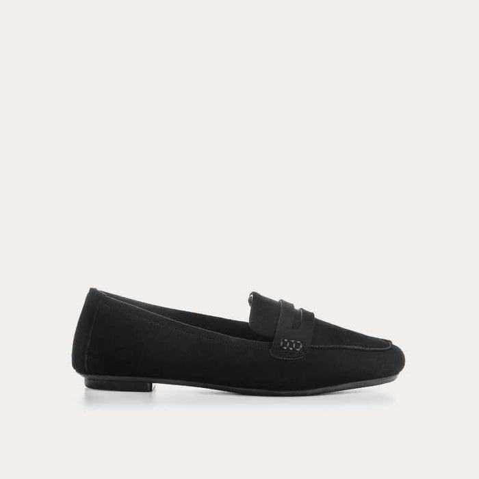 The REQINS HEMA Suede Loafer in Noir features a classic black silhouette, low heel, leather insole, and decorative front strap, shown against a plain light background.