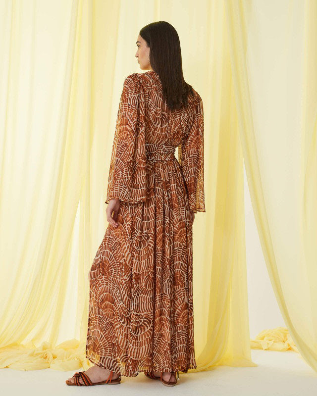 The SFIZIO - RUST PRINT RUFFLED DRESS by SFIZIO is a long-sleeved, floor-length Italian dress in airy viscose creponne with a cinched waist, ruffled neckline, and abstract brown/beige print on lightweight, semi-sheer fabric.