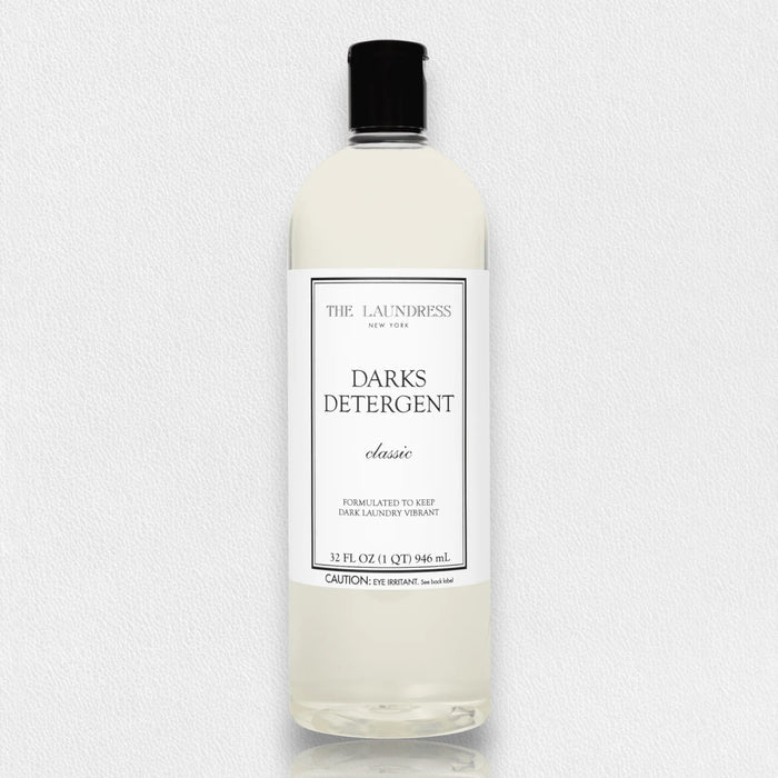 THE LAUNDRESS - DARKS DETERGENT 32OZ comes in a clear bottle with a black cap. This bio-based formula by THE LAUNDRESS helps keep dark laundry vibrant. The white label features elegant black text on the front.