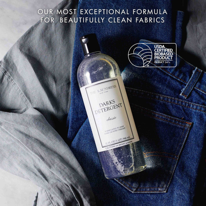 THE LAUNDRESS - DARKS DETERGENT 32OZ comes in a clear bottle with a black cap. This bio-based formula by THE LAUNDRESS helps keep dark laundry vibrant. The white label features elegant black text on the front.