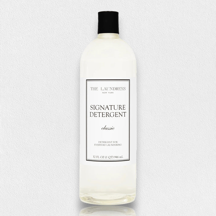 A 32 oz clear plastic bottle of THE LAUNDRESS - SIGNATURE DETERGENT, featuring a black cap and white label, designed for everyday laundry and effective stain removal.