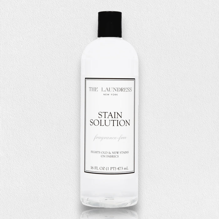 A clear bottle of THE LAUNDRESS - STAIN SOLUTION 16OZ enzyme cleaner, fragrance-free, removes old and new stains from fabrics.