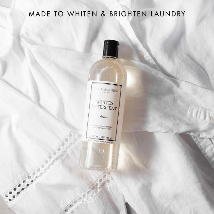 A clear plastic bottle with a black cap labeled "THE LAUNDRESS - WHITES DETERGENT 32OZ." This detergent by THE LAUNDRESS features a bio-based formula specially made for white fabrics.