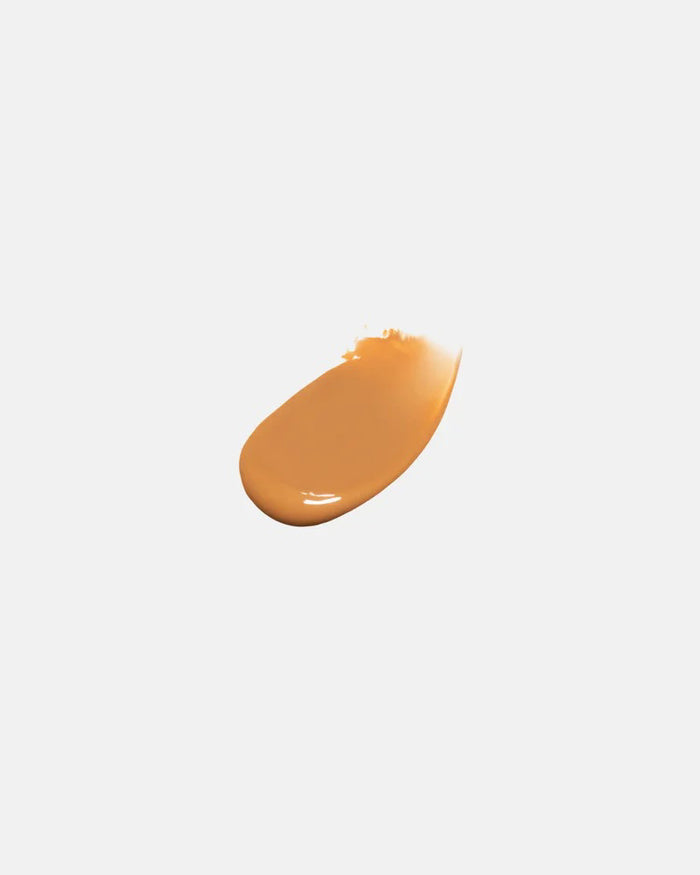 A bottle of U BEAUTY - THE SUPER TINTED HYDRATOR SHADE 8, featuring a white cap and frosted clear body with beige liquid, stands upright against a light gray background.