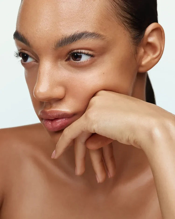 A bottle of U BEAUTY - THE SUPER TINTED HYDRATOR SHADE 8, featuring a white cap and frosted clear body with beige liquid, stands upright against a light gray background.
